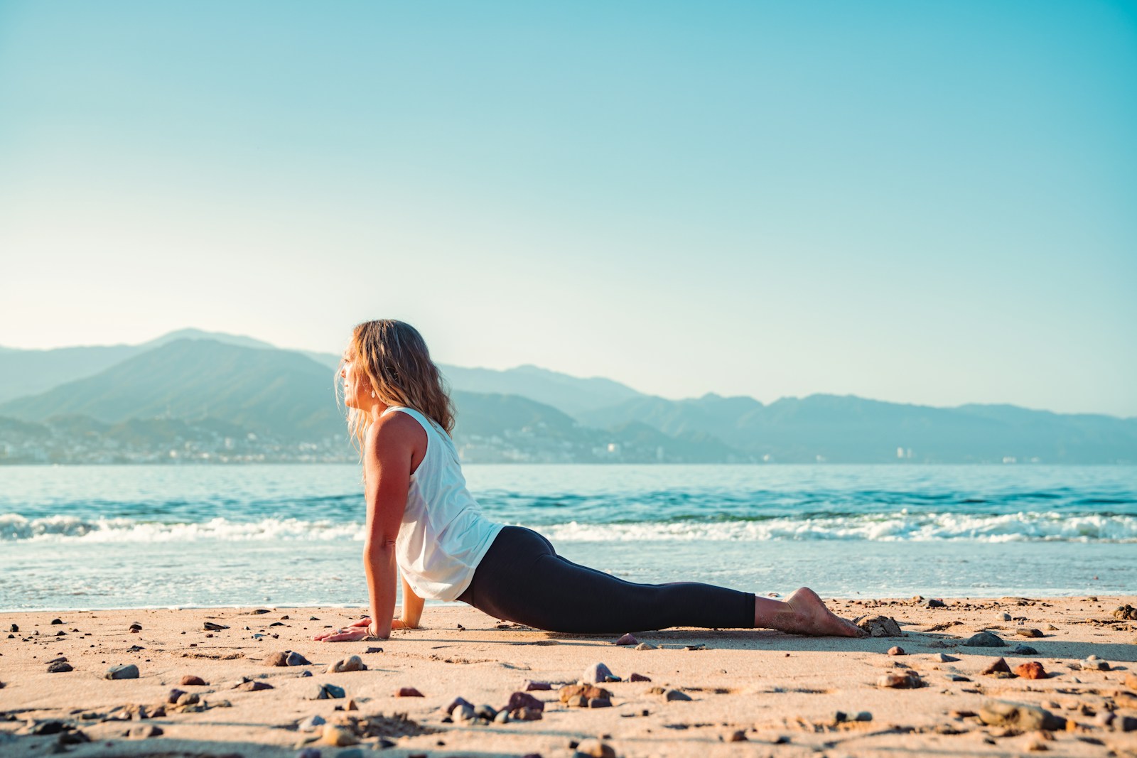 Frau praktiziert Yoga am Strand mit Meerblick